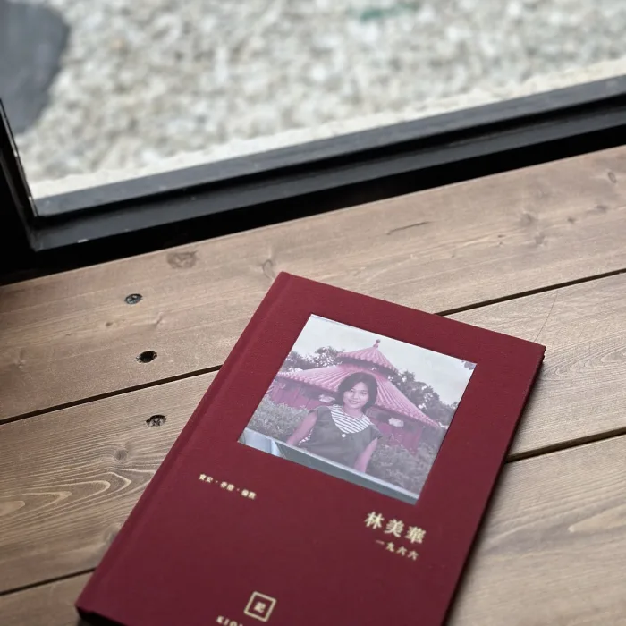 紅色布面燙金長輩故事書封面，內嵌長輩後生時嘅舊相同金色姓名年份